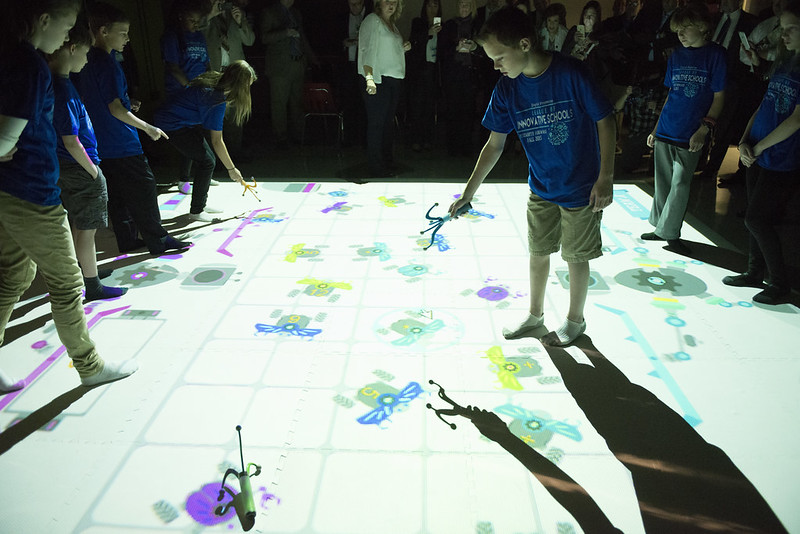 Children play on a floor with a projection on in.