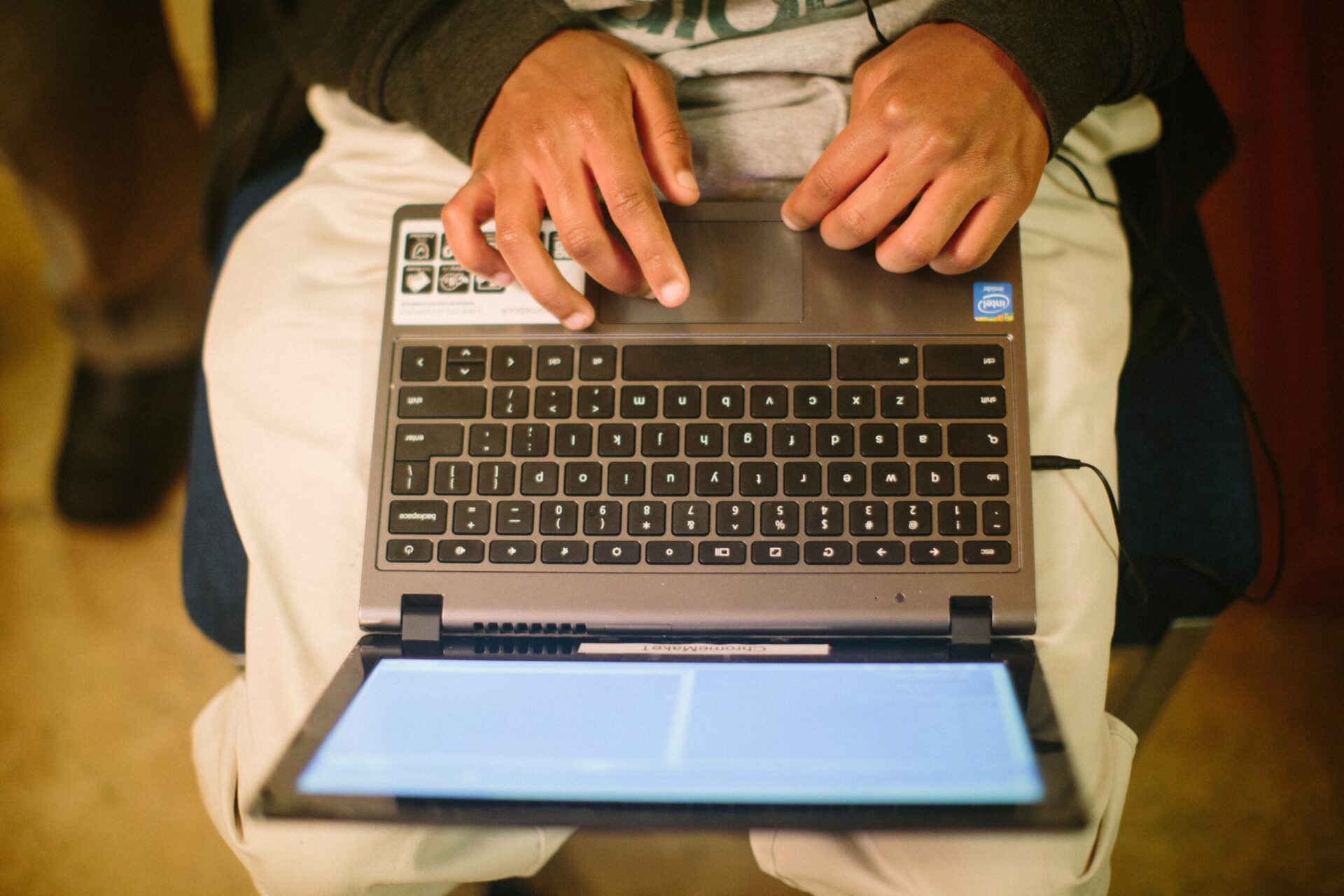 An overhead view of a young person typing on a computer keyboard.