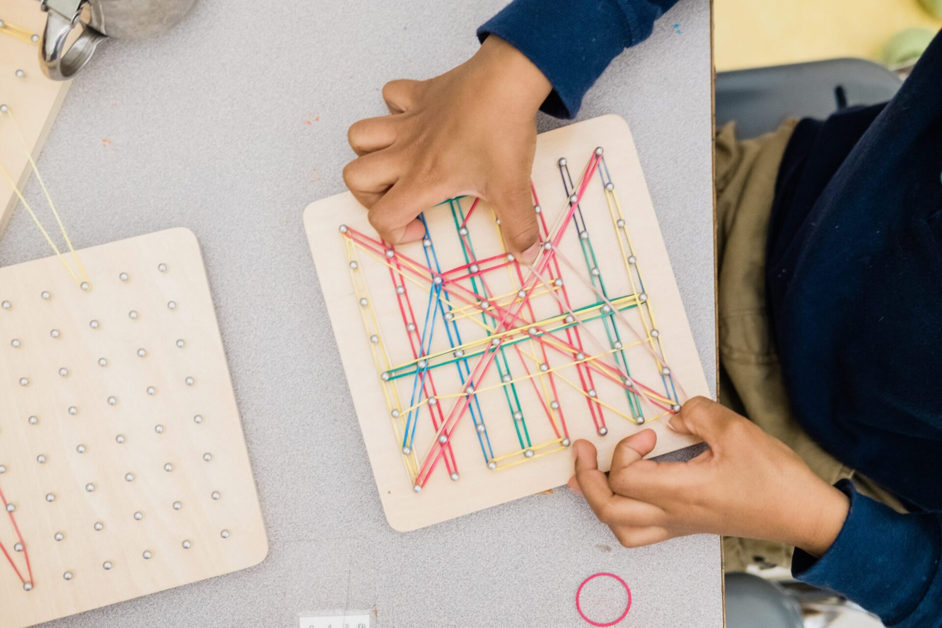 A young learner at Pittsburgh Faison K-5 School connects rubber bands on a pegboard as part the Hatch Partners in Play program.