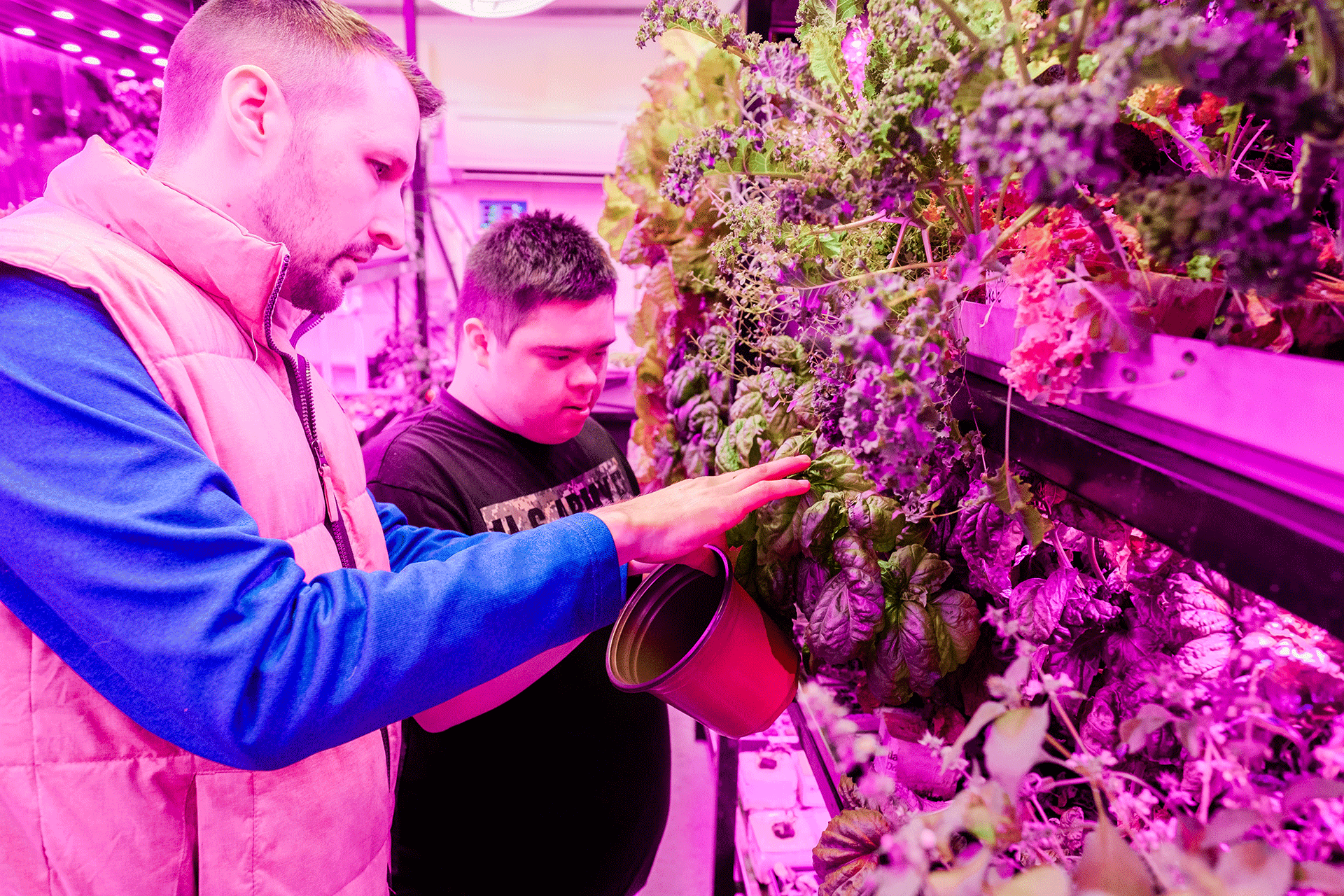 An adult shows a child how to tend a hydroponic garden.