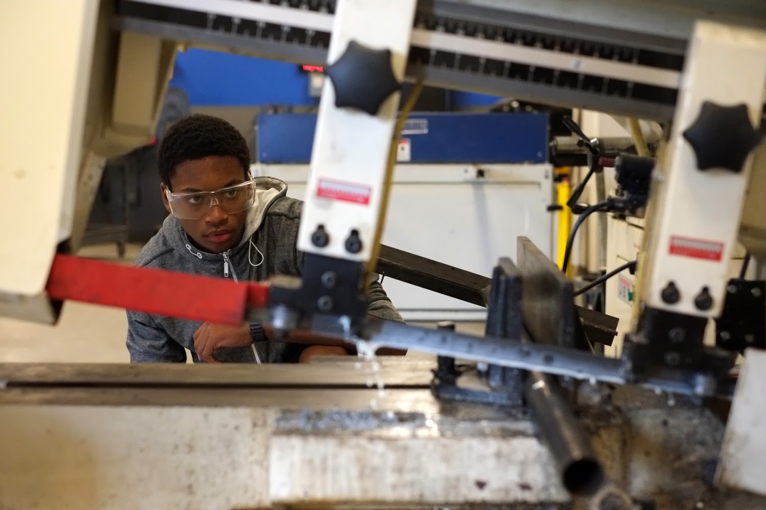 A high school student using fabrication equipment to build a prototype.