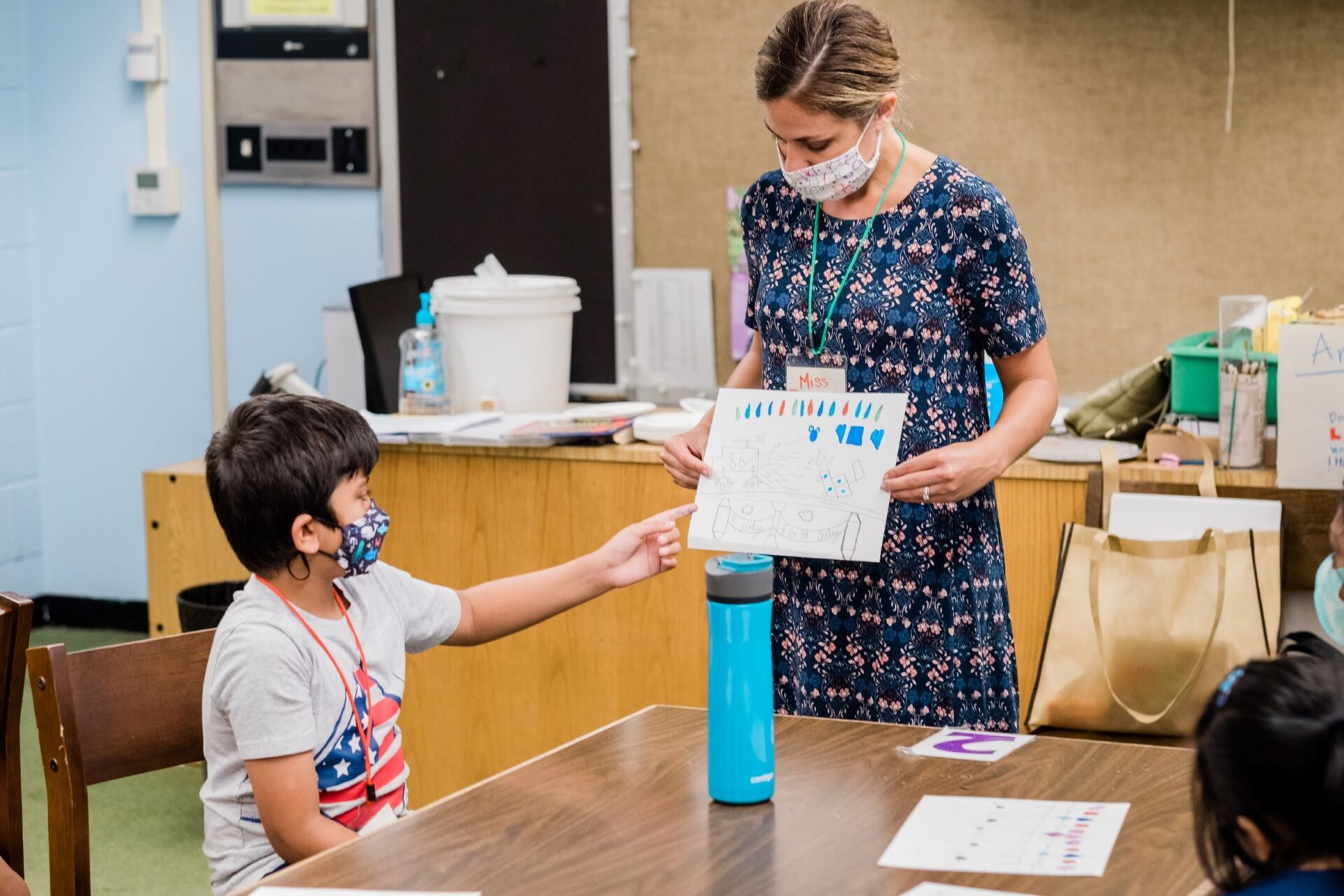 Boy points to an illustration being held by a teacher.