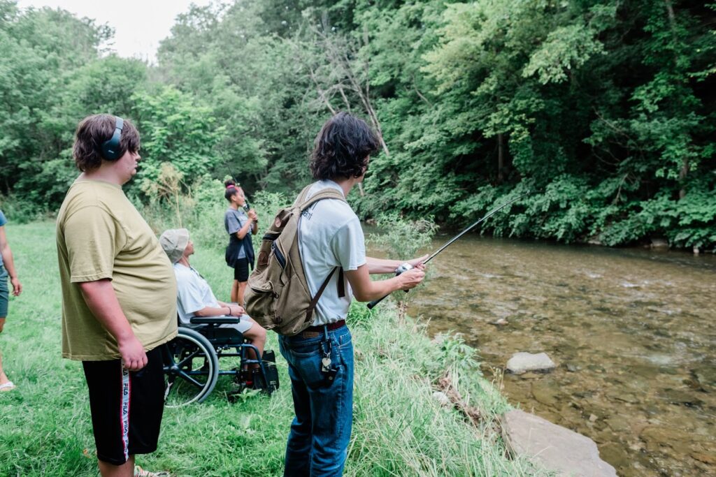 A diverse group of students standing at a riverbank, fishing