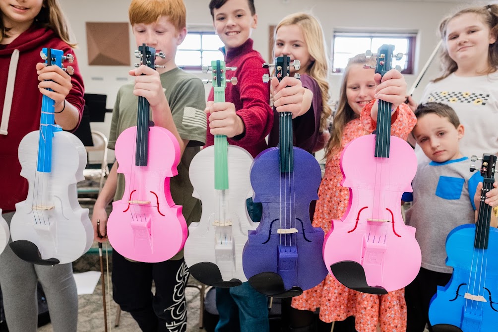 Students holding the violins they 3-D printed at California Area School District as part of their Moonshot grant project