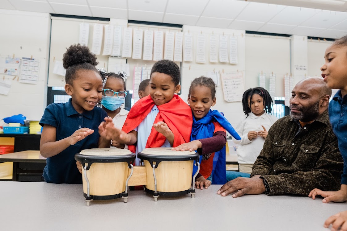 Kindergarteners at Pittsburgh Faison bang on a bongo drum during an imaginary play activity as part of the Hatch Playlab