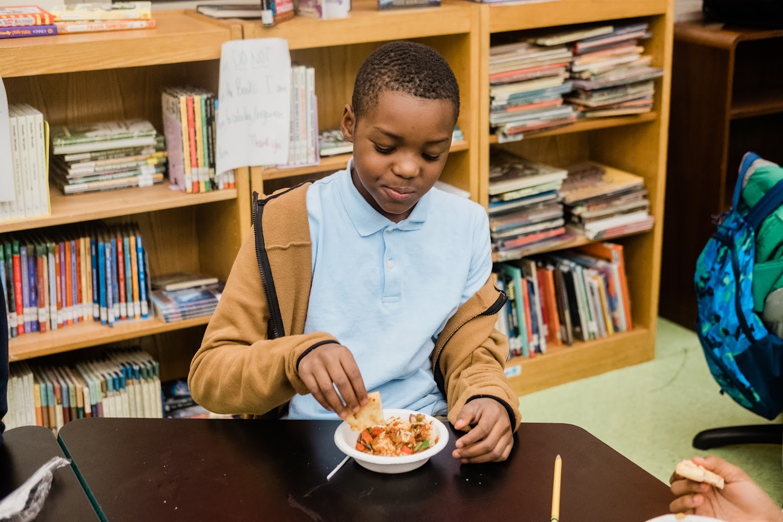 A student enjoys some food cooked during a program of Oasis Farm & Fishery's Moonshot grant