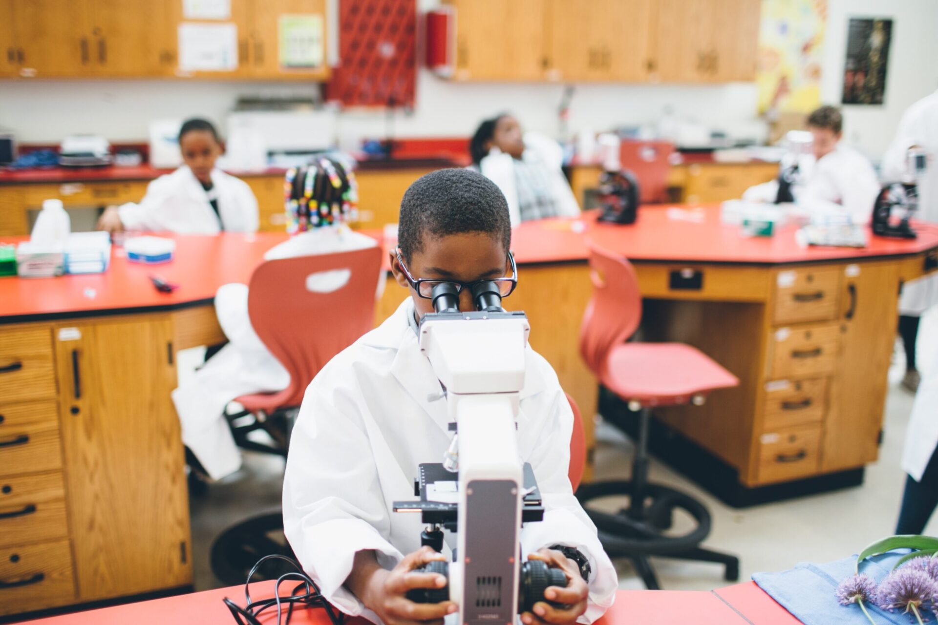 A young Black student works behind a microscope.
