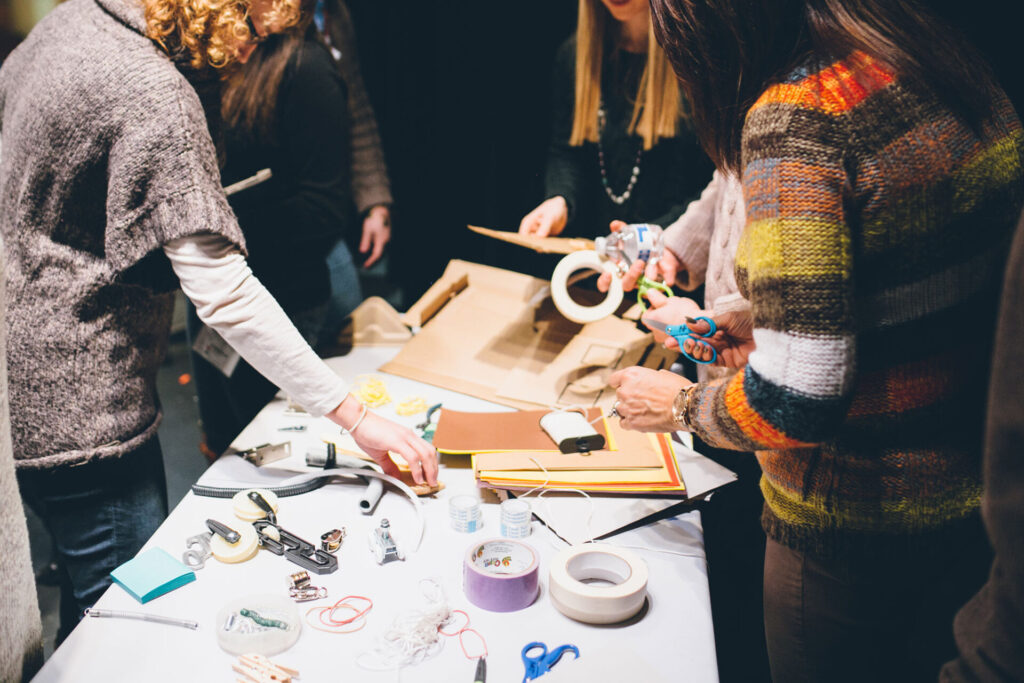 People working around a table with various crafts and utensils.