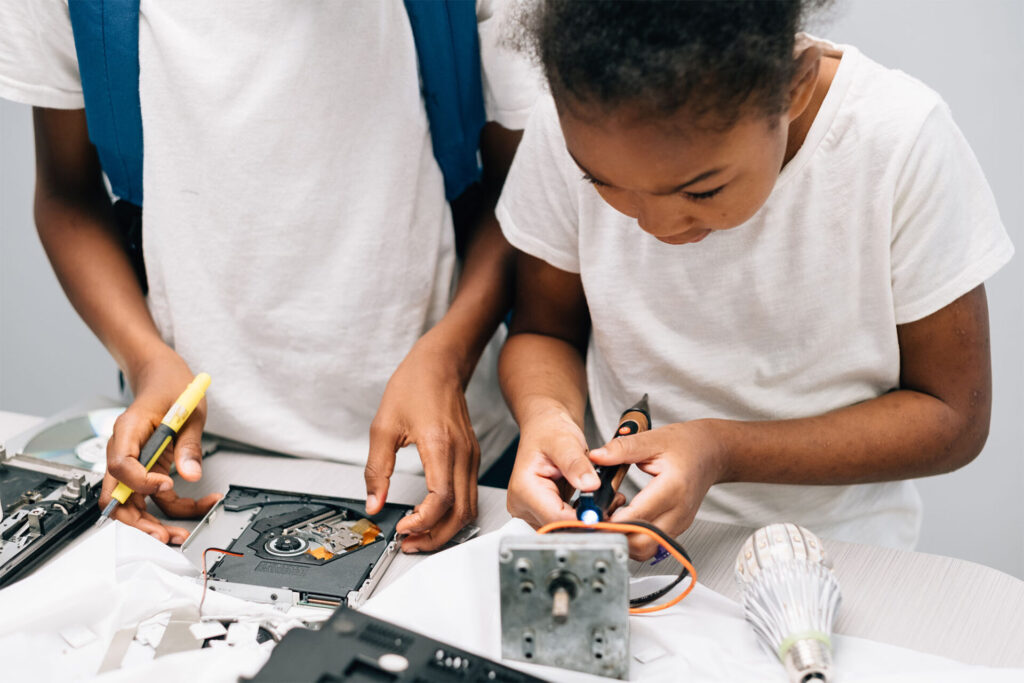 Two young children tooling with computer parts.