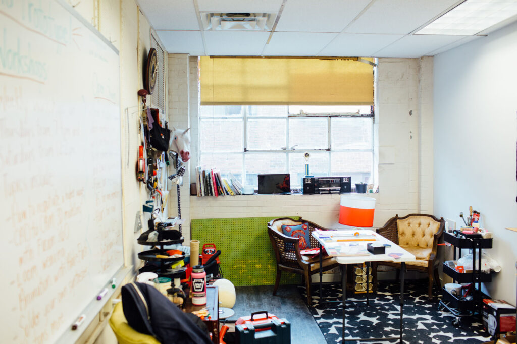 A shot of a room with various object lining the walls and two chairs by a table.