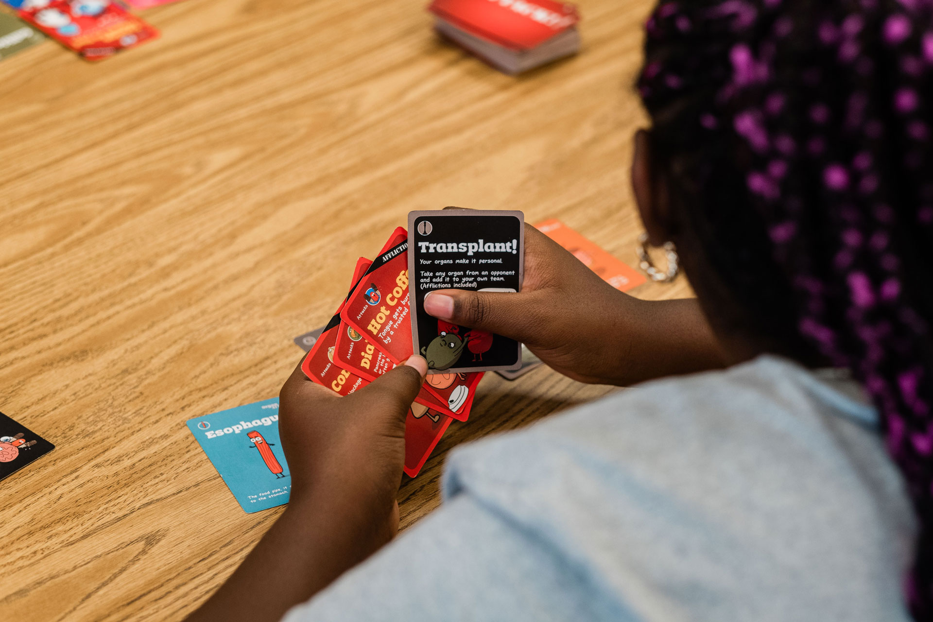 An over-the-shoulder view of a teenage girl playing a card game