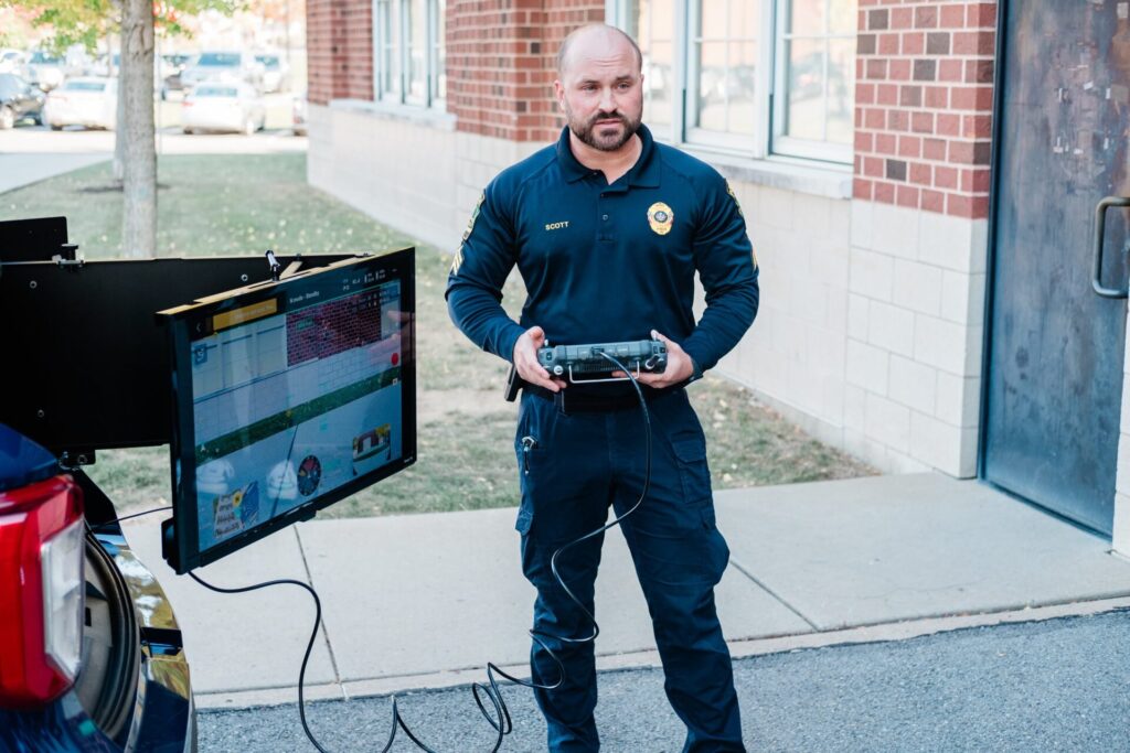 A police officer piloting a drone aircraft with a handheld controller.