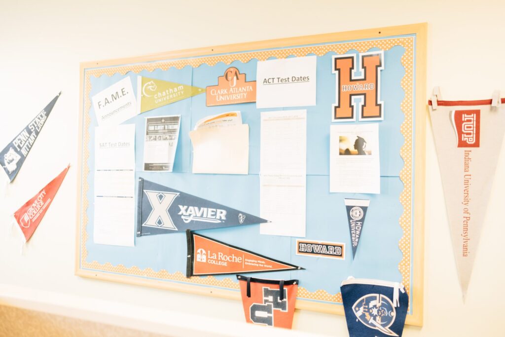 Several college pennants hung on a bulletin board