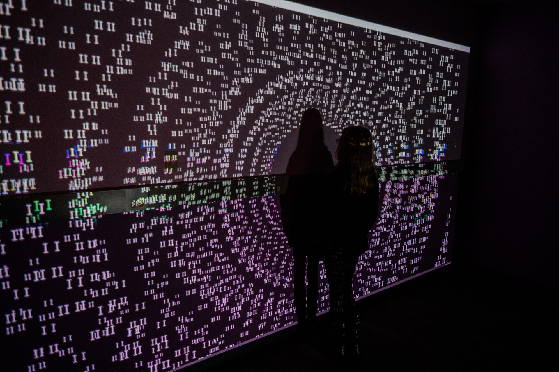 A person stands in front of a light projection of datapoints.