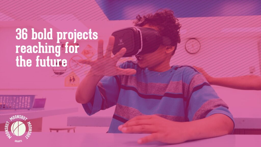 A boy wears a VR headset and reaches out with one hand.